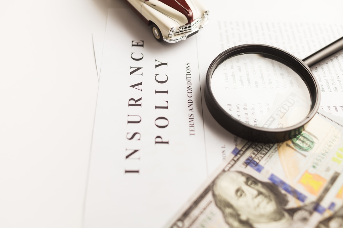 保険証書（INSURANCE POLICY）を虫眼鏡で確認するイメージ